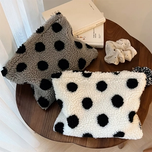 Detailed view of plush lamb wool makeup bags with polka dots on a rustic wooden table