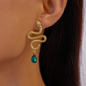 Close-up of golden snake earring with pear-cut green gemstone on a model's ear
