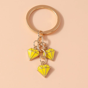Detail of yellow enamel diamond-shaped pendants on a golden metal keychain for bags