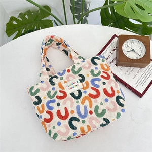 Gros plan du sac matelassé avec motifs en U colorés et étiquette de marque sur blanc
