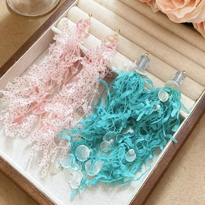 Detail of pink and teal mesh fringe earrings with pearls and sequins on linen