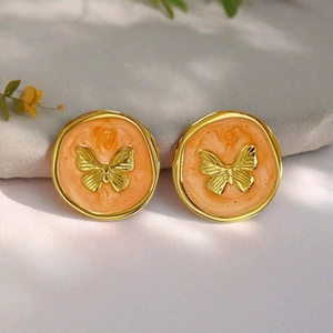 Close-up of vintage gold butterfly earrings with orange enamel and textured wings
