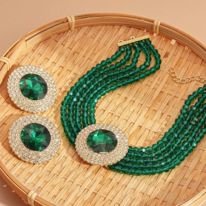 Vintage green glass rhinestone necklace and earrings set on a woven tray
