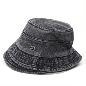 Detail of vintage washed denim bucket hat featuring a circular gold metal logo ornament