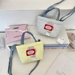 Détail de mini sacs matelassés en cœur jaune et bleu avec des anses en denim