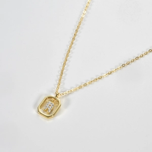 Close-up of a gold S925 silver hexagon pendant with a diamond-studded H-letter detail