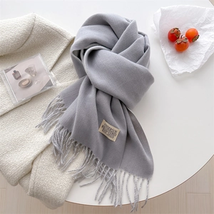 Close-up of light grey cashmere-like scarf with fringe detail and woven brand label