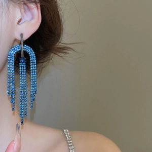 Détail de boucles d'oreilles pompons en strass bleu cobalt avec design en cascade