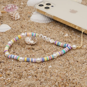 Bohemian colorful clay bead phone lanyard with LOVE pearl charm on a beach background