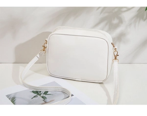Detail of white PU leather crossbody camera bag with gold metal buckle and adjustable strap