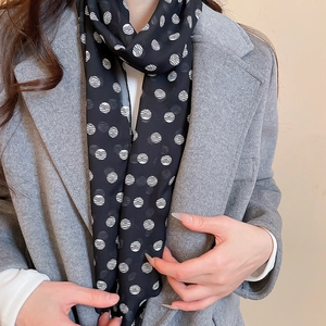 Elegant polka dot scarf necklace detail paired with a minimalist grey wool coat