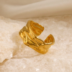 Irregular textured gold open ring with lava wave pattern on white stone background