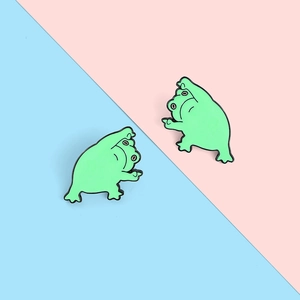 Détail de deux broches en émail grenouille verte aux poses de yoga sur fond pastel doux