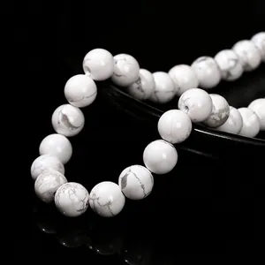 Polished natural white howlite round beads with grey veins on a black background