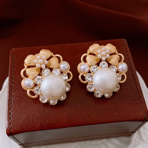 Detailed macro view of vintage gold-plated pearl earrings with a bow on a leather box
