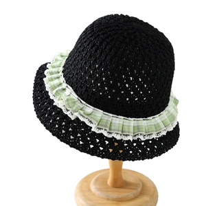 Black woven straw sun hat with green plaid ribbon and white lace trim on wooden stand