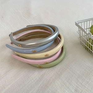 Five assorted colors PU leather headbands with gold logo coin on minimalist fabric
