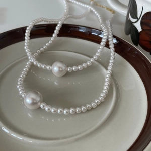 Elegant 925 silver pearl necklace set with gold clasp on a ceramic plate decor