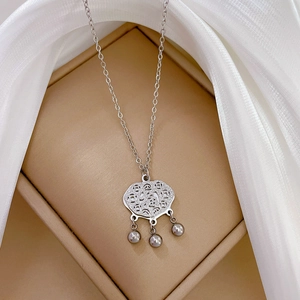Detail of titanium steel ruyi lock pendant with hanging pearls on a silk background