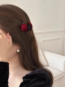 Detail of elegant dark red rose flower hair claw clip worn on a woman's wavy hair