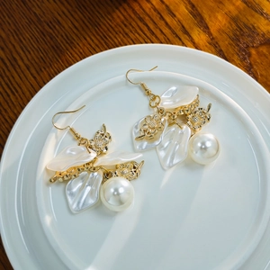 French vintage white petal and pearl drop earrings displayed on a white ceramic plate