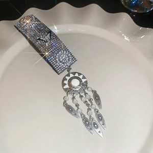 Detailed macro of bohemian silver hairclip with rhinestones, pearls and metallic tassels
