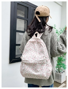 Detailed view of canvas floral backpack with pink flowers on beige background