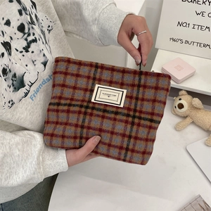 Detail of vintage plaid wool makeup bag with PLEASANT TIME label held by hands