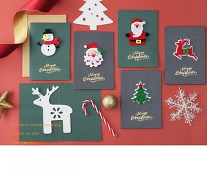 Detail of felt 3D Christmas cards with Santa and reindeer motifs on festive red background