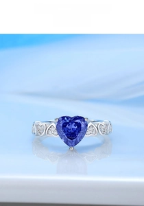 Close-up of heart-cut sapphire ring with side heart hollows and silver stones