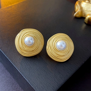 Detail of vintage gold twisted circle stud earrings with elegant faux pearl centers