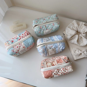 Detail view of four quilted floral cotton makeup bags with top zipper and woven labels