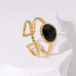 Detail of adjustable gold ring with black oval stone on a textured stone display