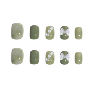Short green press-on nails with white 3D flowers, marble patterns and butterfly bows