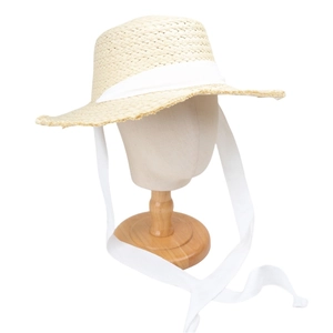 Detail of summer straw sun hat featuring wide brim and long white decorative lace ribbons