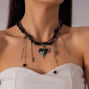 Macro detail of gothic heart pendant with cross and dark crushed stone bead tassels