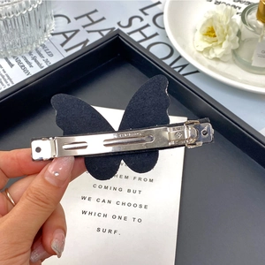 Detailed view of an elegant black butterfly hair clip with a silver metal alligator clasp
