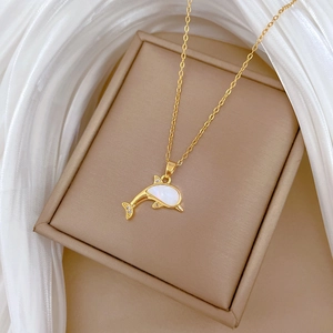Elegant gold dolphin necklace with shell inlay and diamonds on a beige jewelry box