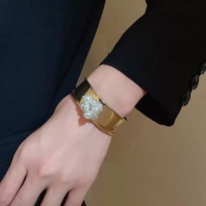 Detailed view of wide gold cuff bracelet featuring elegant white pearl flower clusters