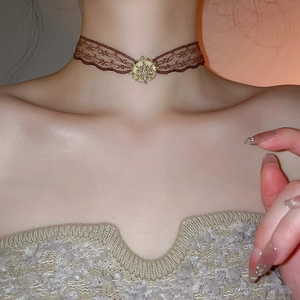 Macro detail of a brown lace choker featuring a gold starburst pendant with pearl inlay