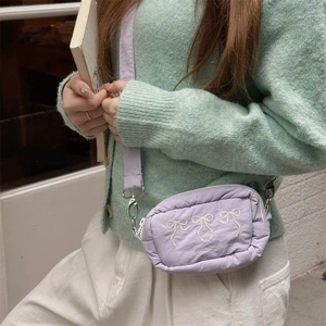 Detail der lila Nylon-Umhängetasche mit weißem Schleifen-Stick und silbernem Metallhaken