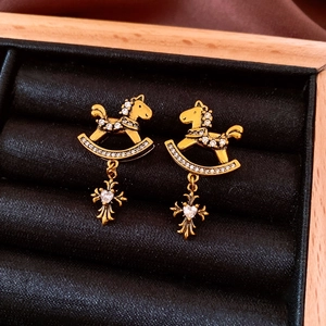 Macro detail of vintage gold horse earrings with zircon cross pendant in a jewelry box