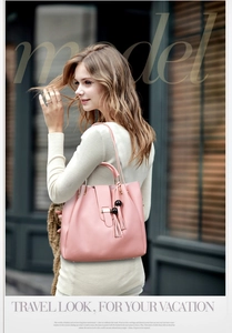 Close-up of pink leather handbag with metallic buckle and stylish pompom tassels