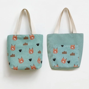 Detail of green canvas tote bag featuring cartoon fox prints and a back storage pocket