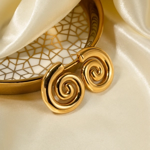 Macro detail of gold spiral hoop earrings on a decorative plate with silk fabric