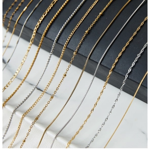 Detail of gold and silver stainless steel water wave and box chains on marble