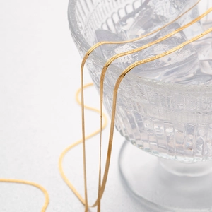 Close-up of flexible 5mm gold snake chain draped elegantly in a glass with ice