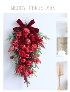 Close-up of a Christmas teardrop swag with red velvet bow, pine needles, and berries
