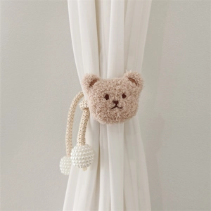 Detail of plush bear head curtain tieback with woven rope and large white pearl closure