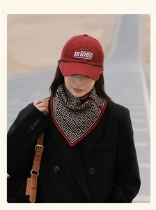 Detail shot of a geometric pattern scarf with red trim and white embroidered baseball cap